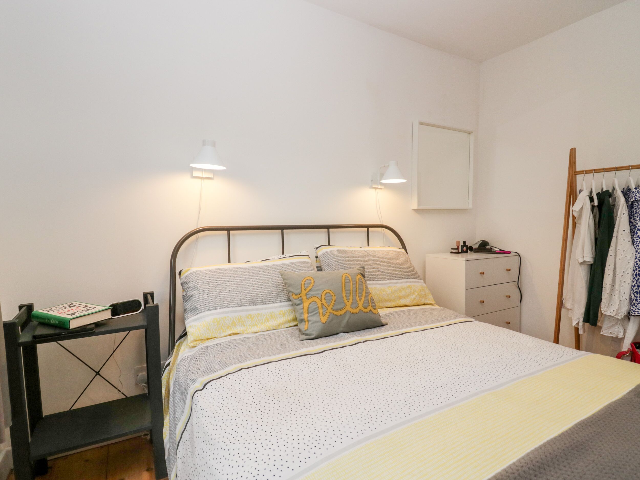 A neatly arranged bedroom with a bed, bedside tables, and a wardrobe.