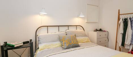 A neatly arranged bedroom with a bed, bedside tables, and a wardrobe.