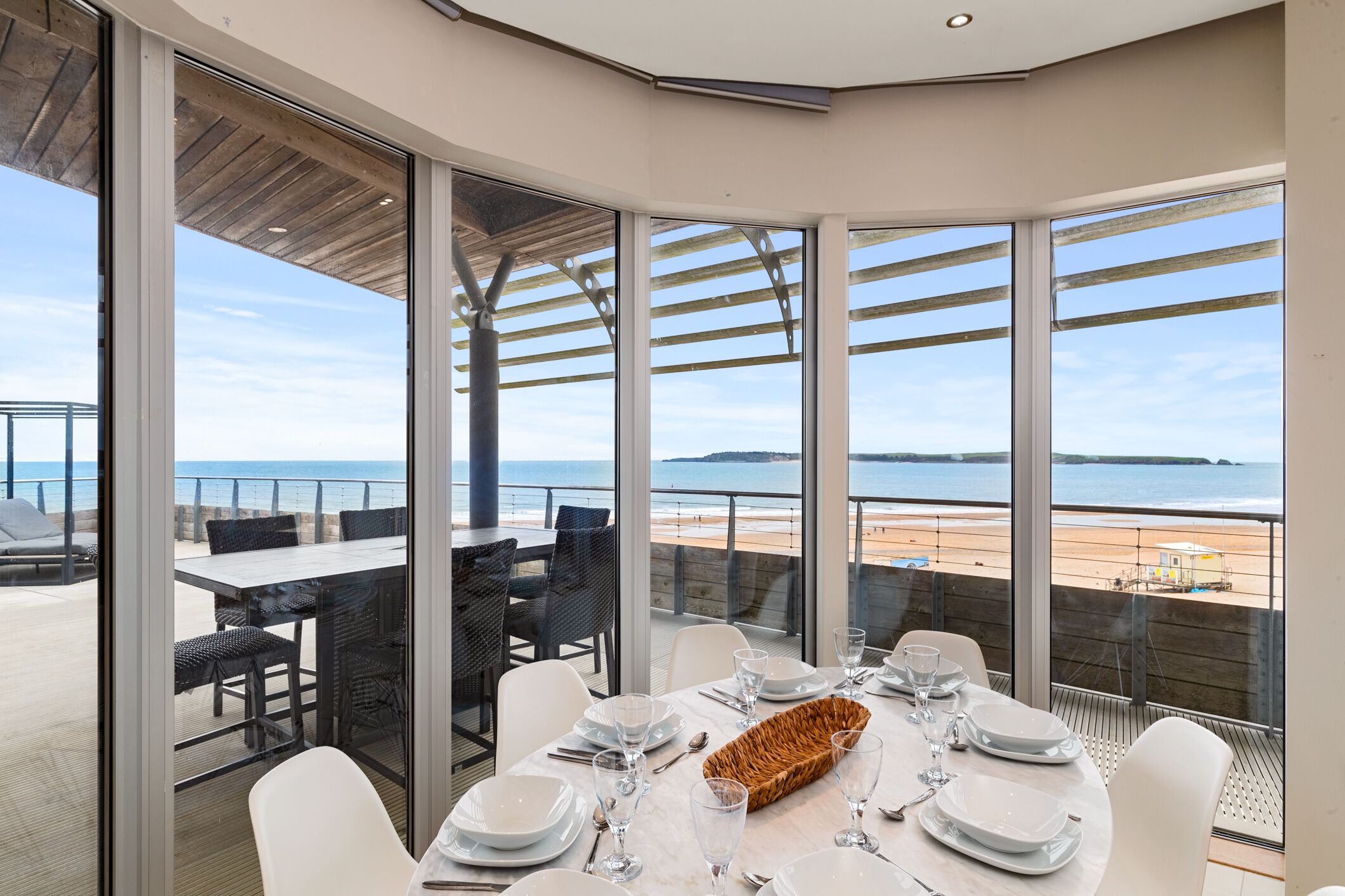 Un coin repas avec une table dressée pour quatre personnes, donnant sur une plage.