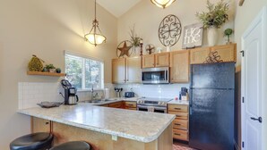 A kitchen with a central island, wooden cabinets, a black refrigerator, and a microwave. - Dog-friendly Pagosa Springs Condo Near Hot Springs (Pagosa Springs)