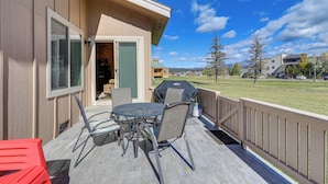 A covered patio with a table and chairs, a barbecue grill, and a view of a grassy area with trees and buildings in the background. - Dog-friendly Pagosa Springs Condo Near Hot Springs (Pagosa Springs)