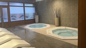 Un área de spa con dos jacuzzis, techo de madera y un ventanal con vidrio esmerilado.
