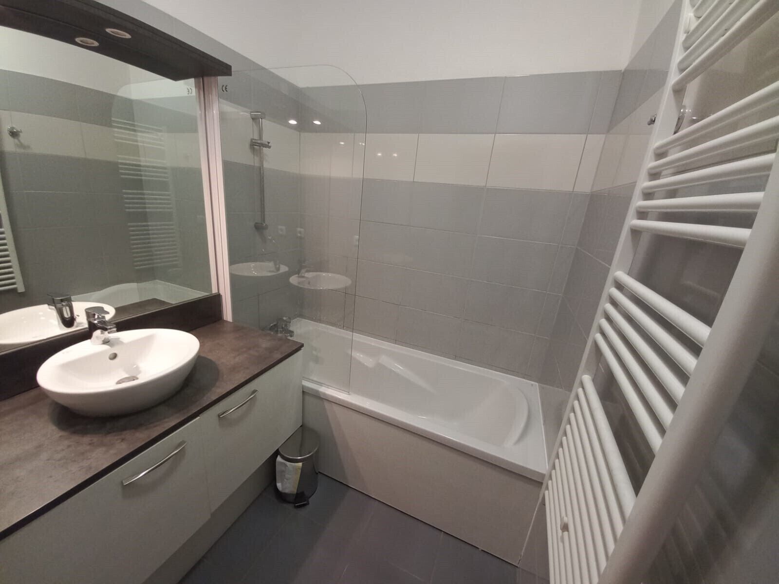 Ein modernes Badezimmer mit einem großen Spiegel, einem Waschbecken, einer Badewanne und einer Dusche.