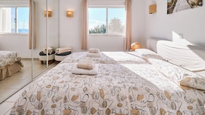 A bedroom with two beds, a large mirror, and a view of the outdoors. - Apartment Buenos Momentos (Carvoeiro)