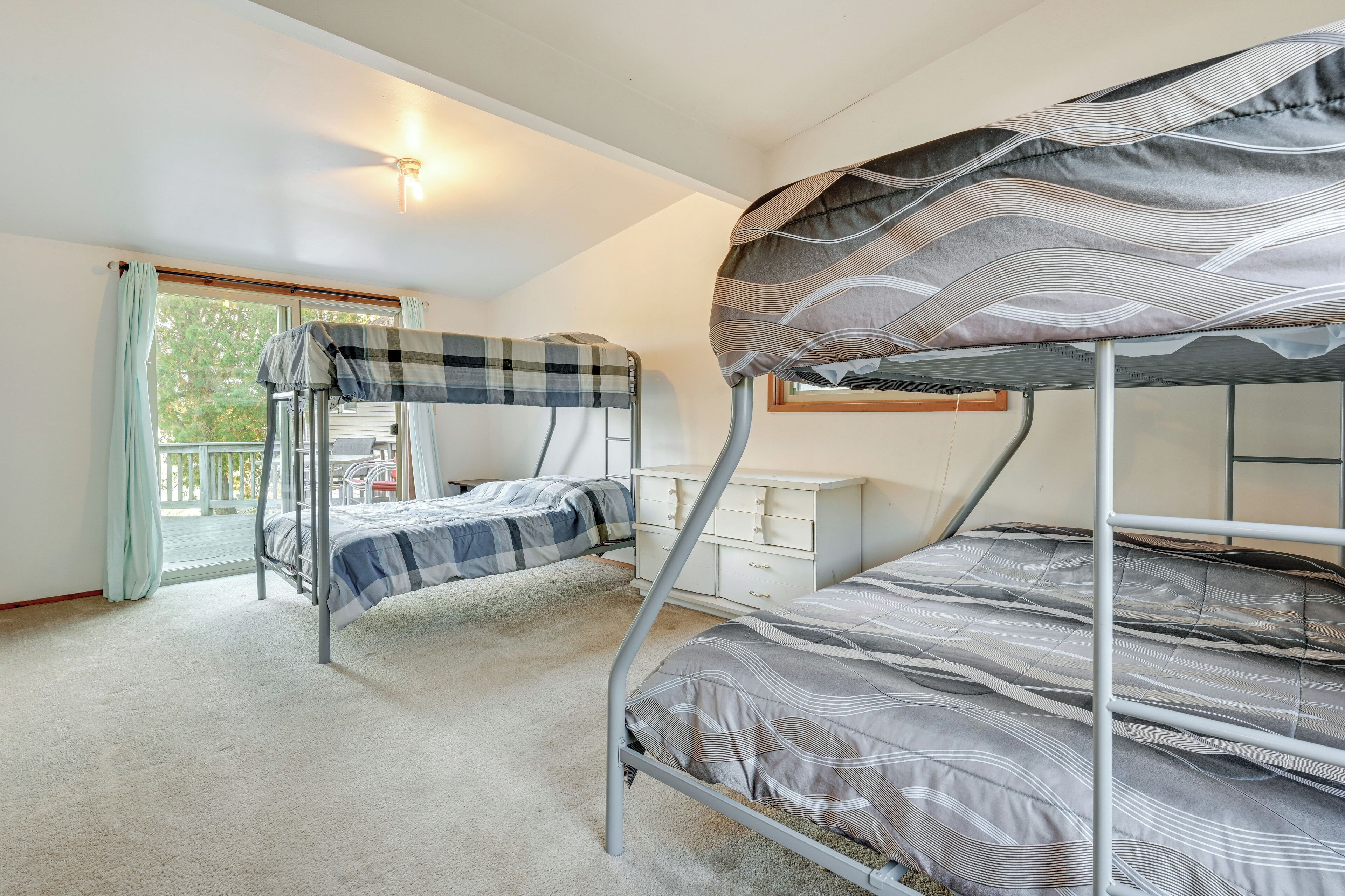 A bunk bed room with a window, a desk, and a chair.