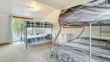 A bunk bed room with a window, a desk, and a chair.