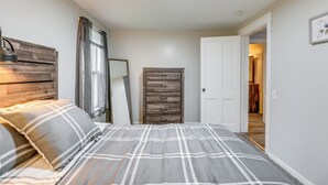 A bedroom with a bed, a dresser, and a door leading to another room. - Central Auburn Apartment w/ Porch: Pets Welcome! (Auburn)