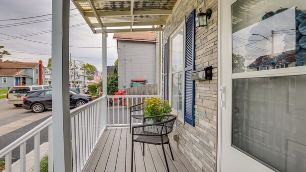 A covered porch with a railing, a window with shutters, and a chair. - Central Auburn Apartment w/ Porch: Pets Welcome! (Auburn)