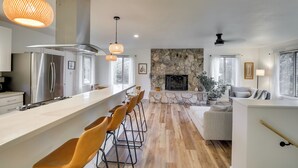 A modern kitchen with a long island, bar stools, and pendant lighting. - Serene Palmer Home: Walk to Downtown & Riverfront! (Palmer)