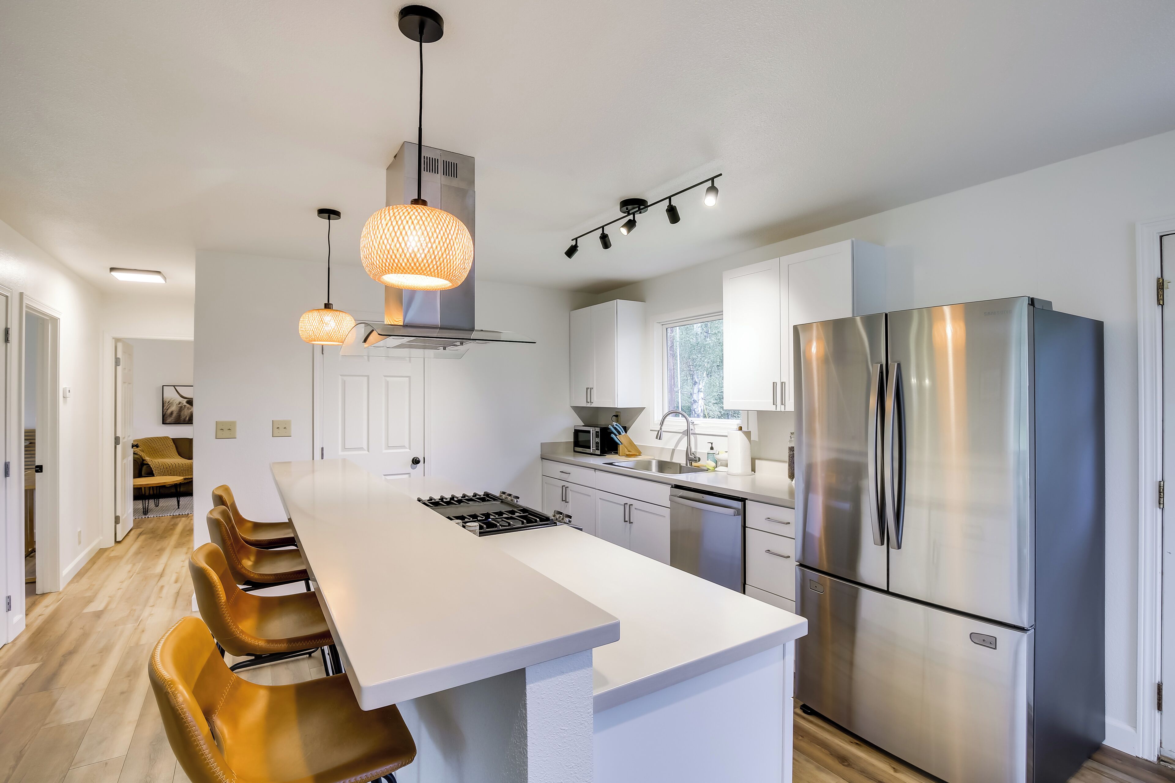 A modern kitchen with a central island, stainless steel appliances, and pendant lighting.