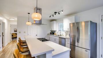 A modern kitchen with a central island, stainless steel appliances, and pendant lighting.