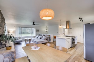 Una cocina moderna con una isla central, armarios blancos y un refrigerador de acero inoxidable.