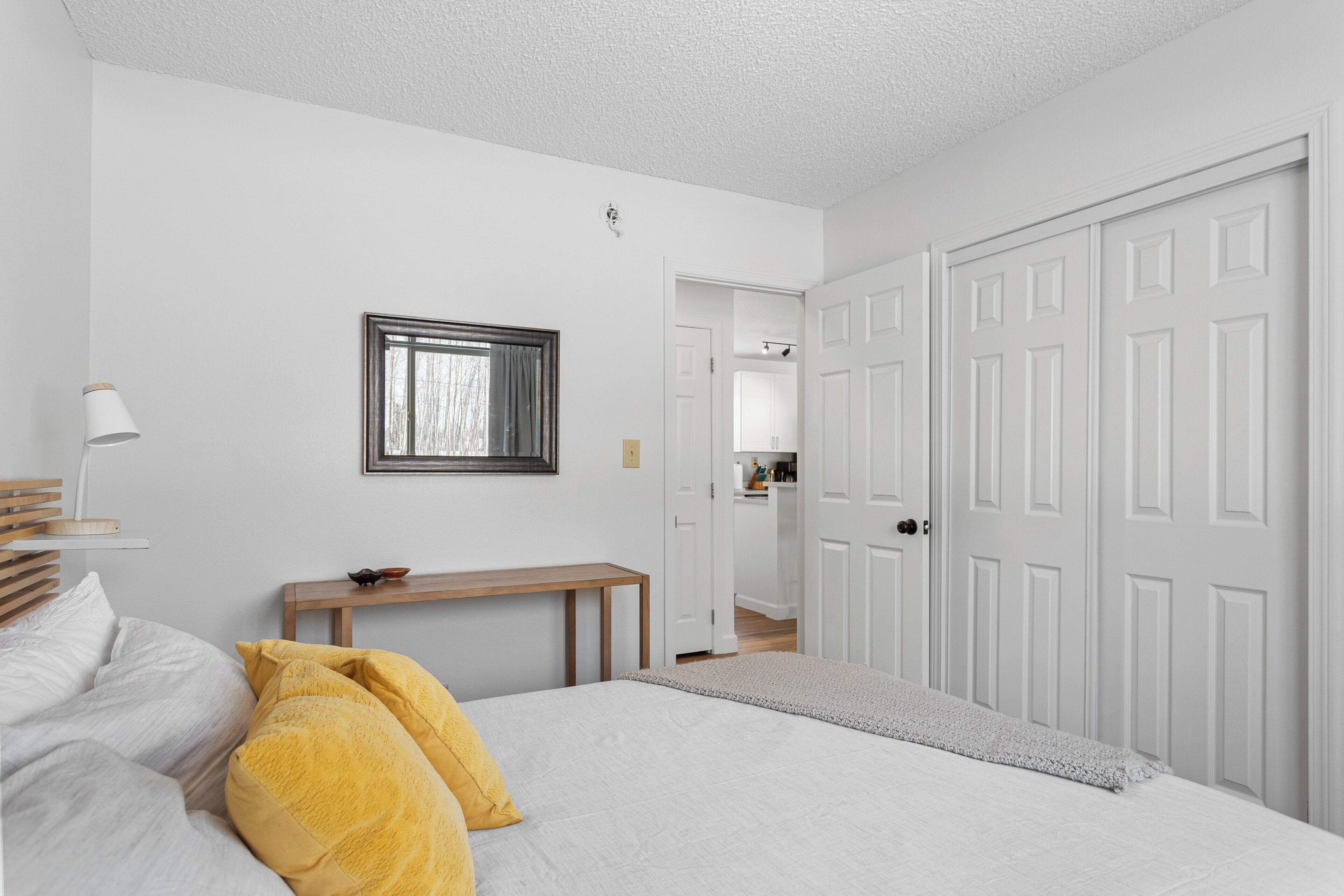 A bedroom with a bed, bedside table, and a wardrobe.