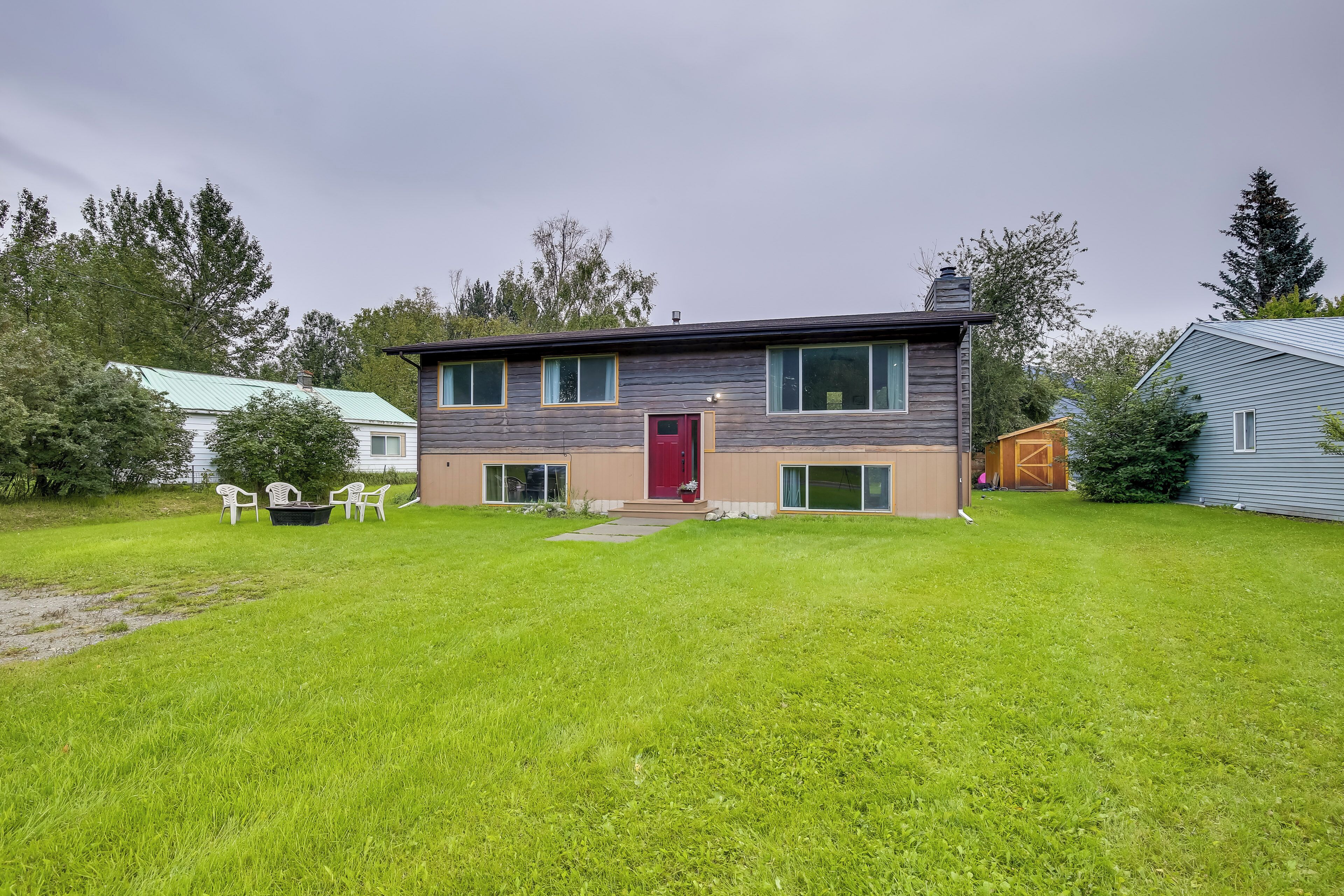 A modern two-story house with a red door, a small front porch, and a well-maintained lawn.