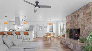 A modern living room with a stone fireplace, wooden flooring, and a grey sectional sofa. - Serene Palmer Home: Walk to Downtown & Riverfront! (Palmer)