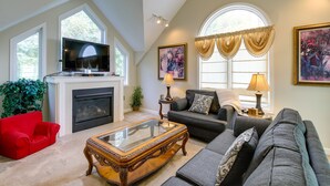 A spacious living room with a fireplace, a television, and a large window with curtains. - Sevierville Vacation Rental: 6 Mi to Dollywood! (Sevierville)