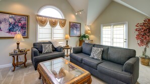 A living room with two grey sofas, a glass coffee table, and a large window with curtains. - Sevierville Vacation Rental: 6 Mi to Dollywood! (Sevierville)