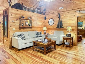 A cozy wooden interior with a sofa, armchairs, and a coffee table.