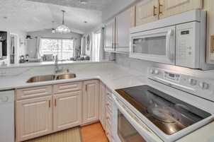 Una cocina moderna con armarios blancos, horno integrado y microondas.