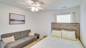 A bedroom with a bed, a gray sofa, a ceiling fan, a window with blinds, and a painting on the wall. - Myrtle Beach Oasis Condo w/ Pool Access! (Myrtle Beach)