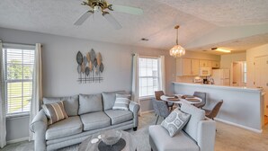 A modern living room with a gray sofa, a coffee table, and a dining area with a small table and chairs. - Myrtle Beach Oasis Condo w/ Pool Access! (Myrtle Beach)