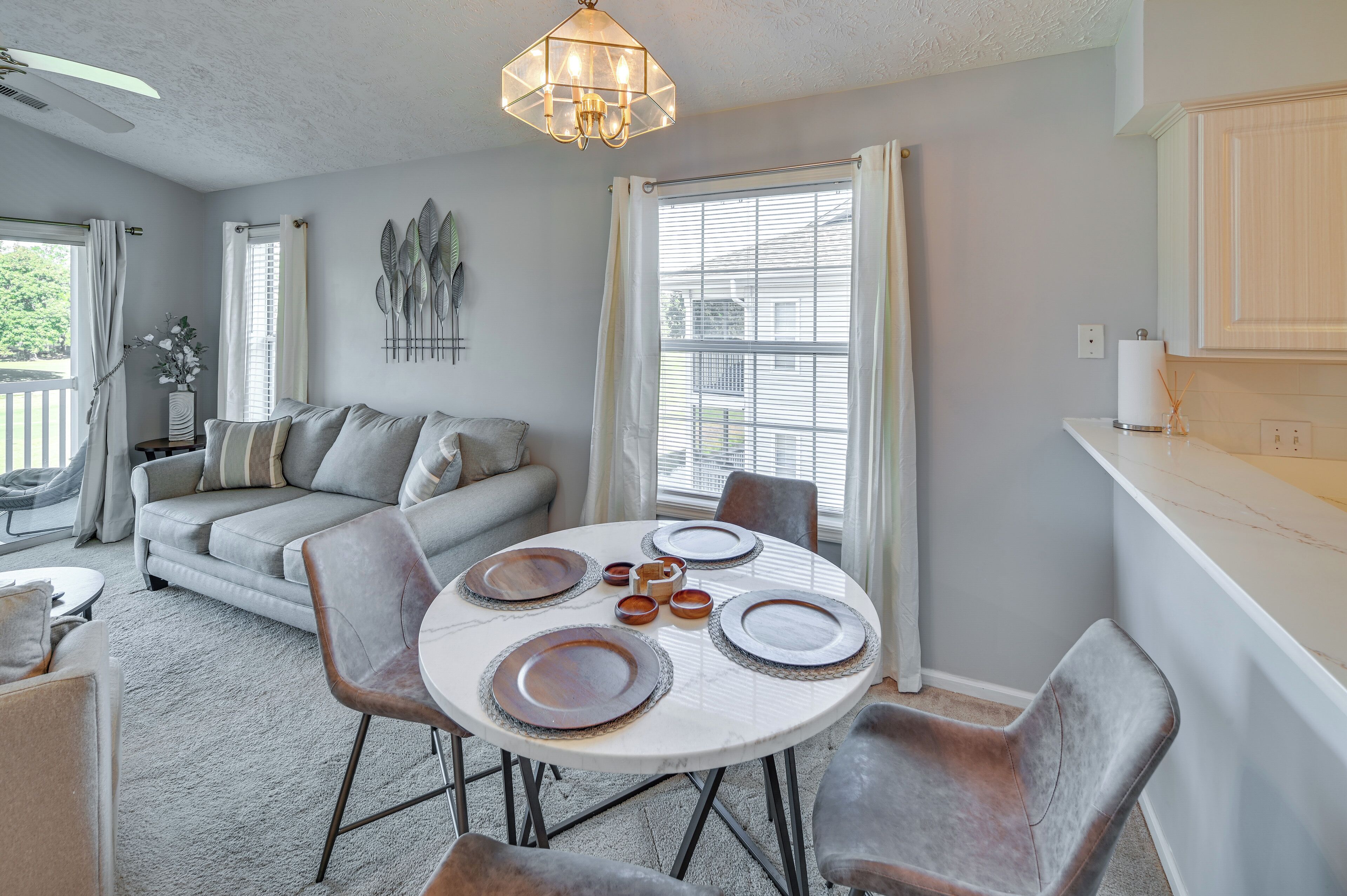 A dining area with a round table set for four, surrounded by grey chairs.