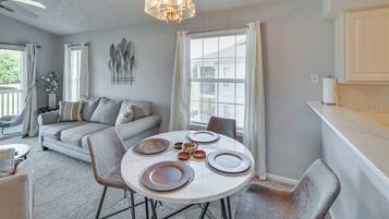 A dining area with a round table set for four, surrounded by grey chairs.