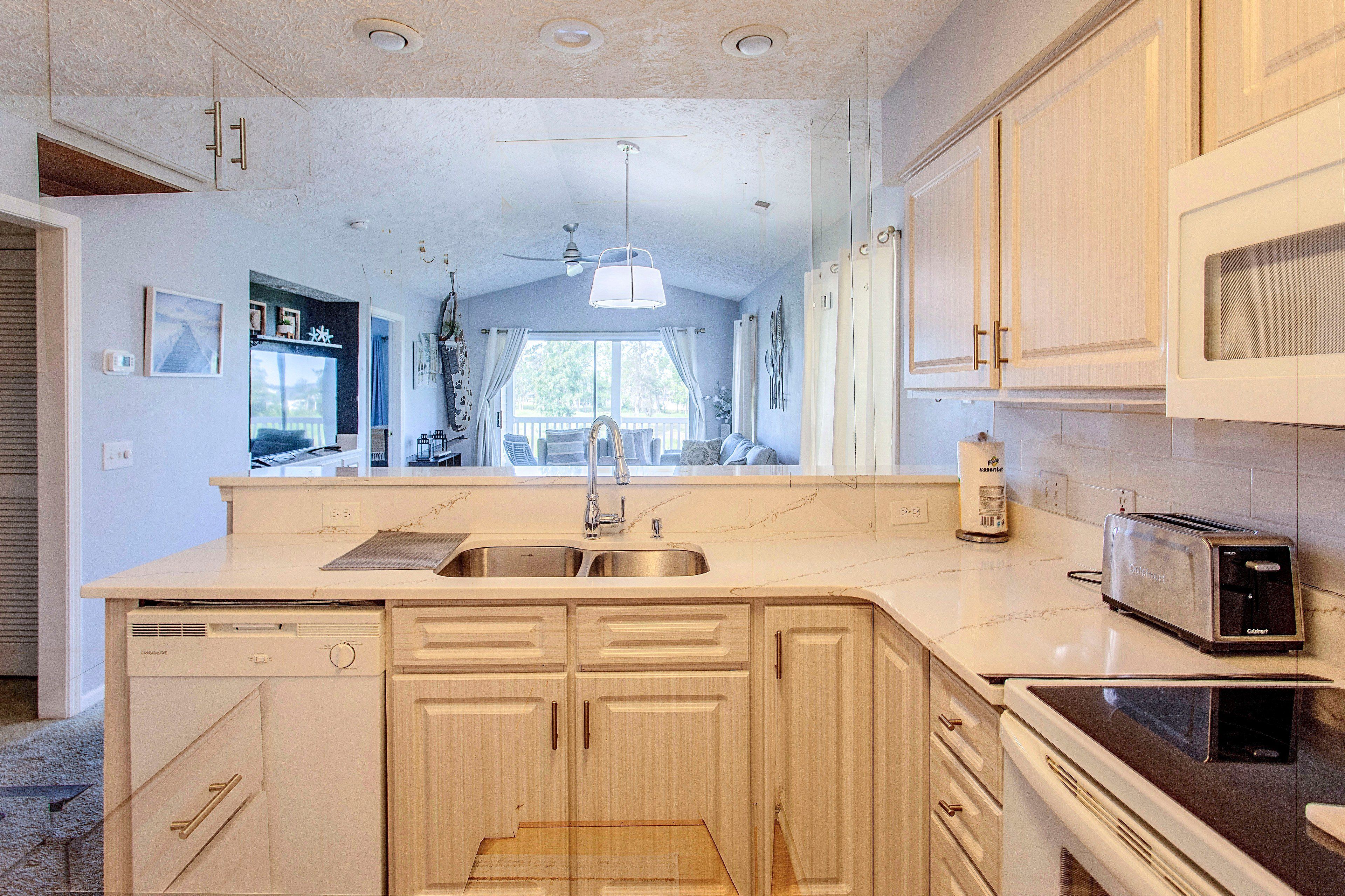 A kitchen with a double sink, a built-in dishwasher, and a toaster.