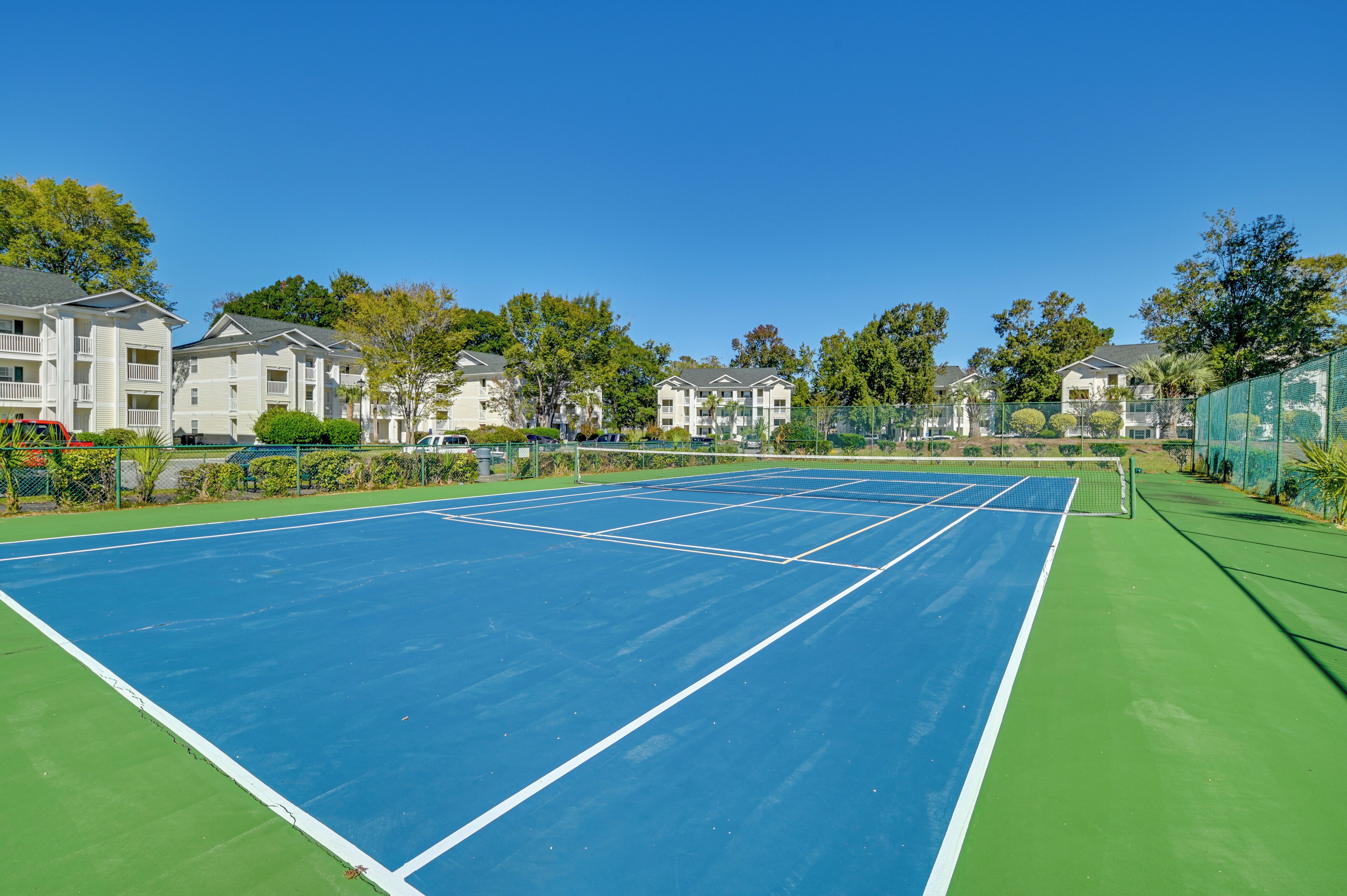 An outdoor tennis court surrounded by apartment buildings.