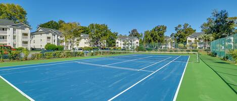 An outdoor tennis court surrounded by apartment buildings.