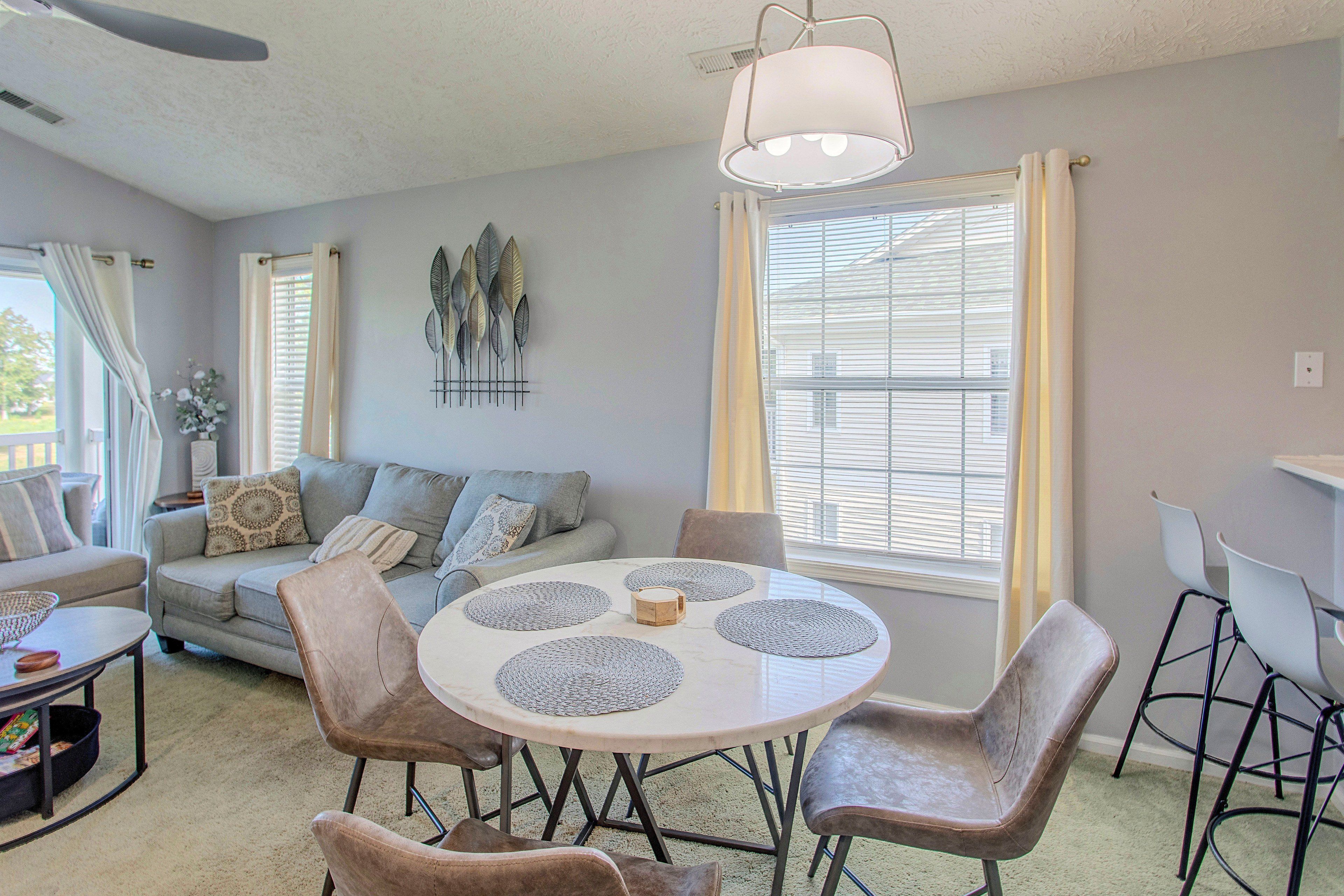 A living room with a round table, chairs, a sofa, and a ceiling fan.