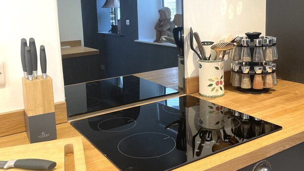 Une cuisine moderne dotée d’une plaque de cuisson à induction noire, d’une planche à découper en bois et d’un bloc à couteaux.