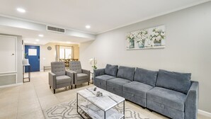Una sala de estar con un sofá gris, dos sillones, una mesa de centro y un cuadro en la pared.