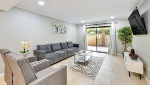 Una sala de estar moderna con un sofá gris, una mesa de centro y un televisor montado en la pared.