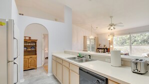 A modern kitchen with a dishwasher, a sink, and a toaster. There is a wooden cabinet and a window with a view of greenery outside. - 20 Mi to Disney: Condo w/ Pool Access in Clermont! (Clermont)