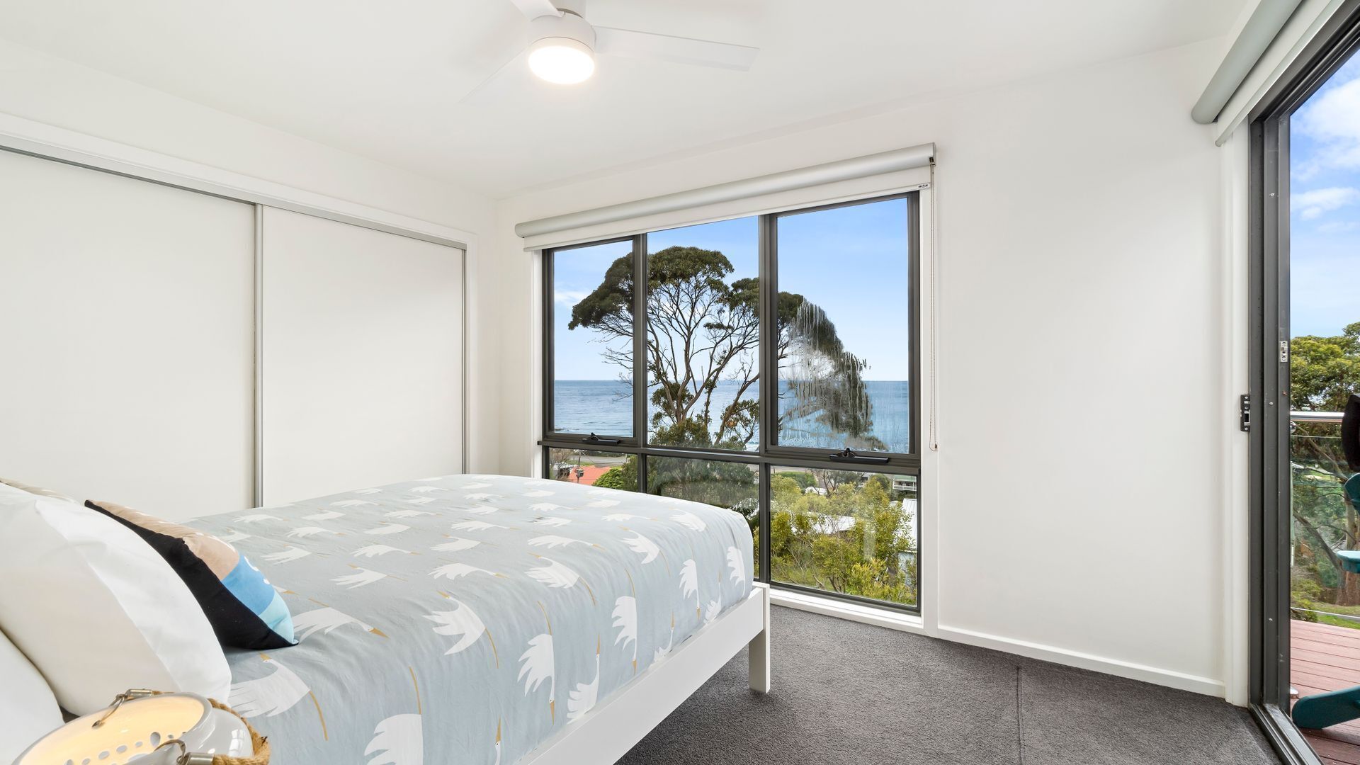 Ein Schlafzimmer mit Bett, Meerblick und einem großen Fenster.
