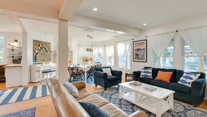 A modern living room with a sofa, coffee table, and a dining area in the background. - Historic Bar Harbor Home ~ 2 Blocks to Main St! (Bar Harbor)
