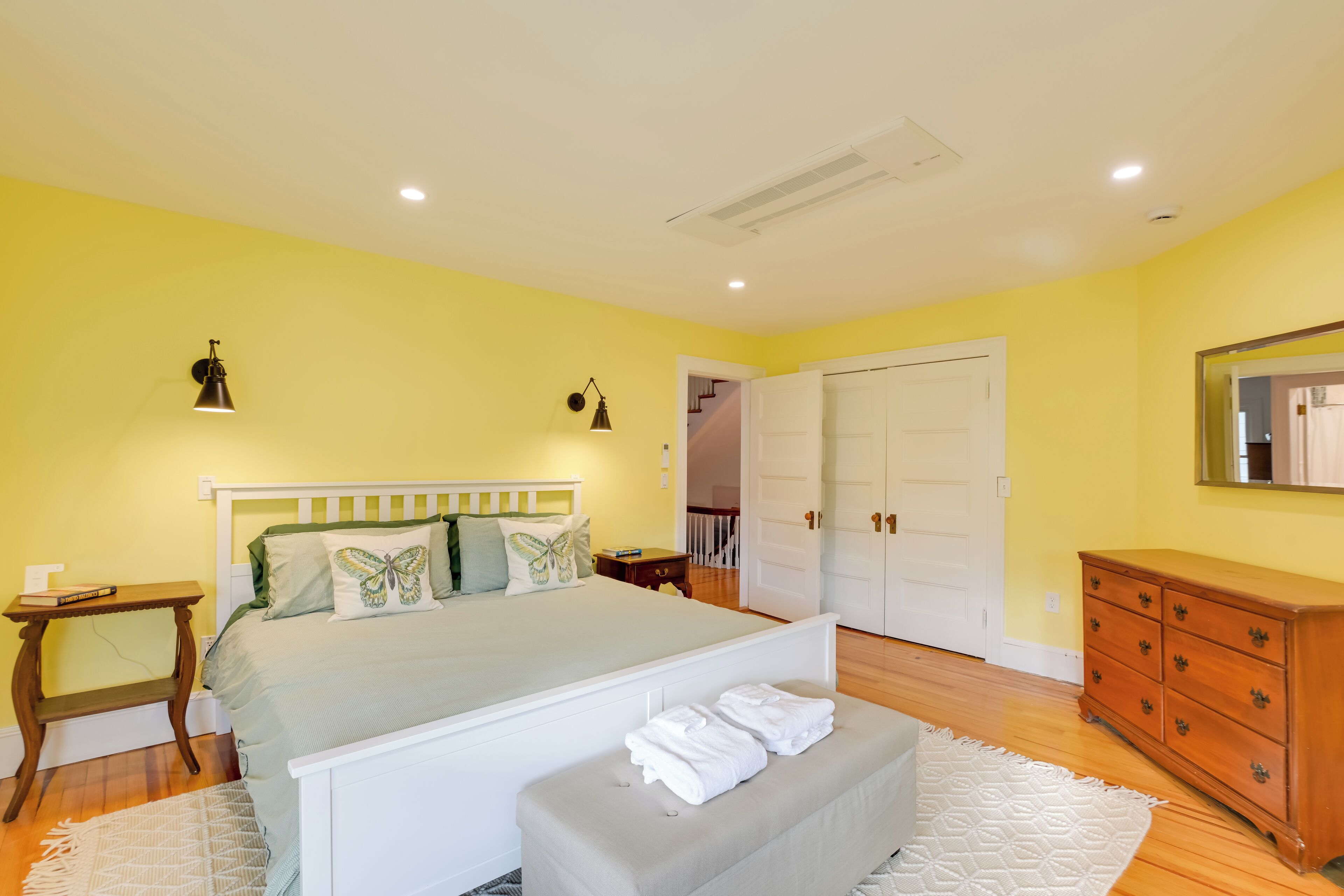Une chambre à coucher comprenant un lit, une table de chevet, une commode et une porte donnant sur une autre pièce.