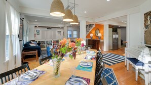 A dining area with a wooden table set for four, surrounded by chairs, with a vase of flowers in the center. - Historic Bar Harbor Home ~ 2 Blocks to Main St! (Bar Harbor)