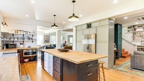 A modern kitchen with a central island, stainless steel appliances, and wooden flooring. - Historic Bar Harbor Home ~ 2 Blocks to Main St! (Bar Harbor)