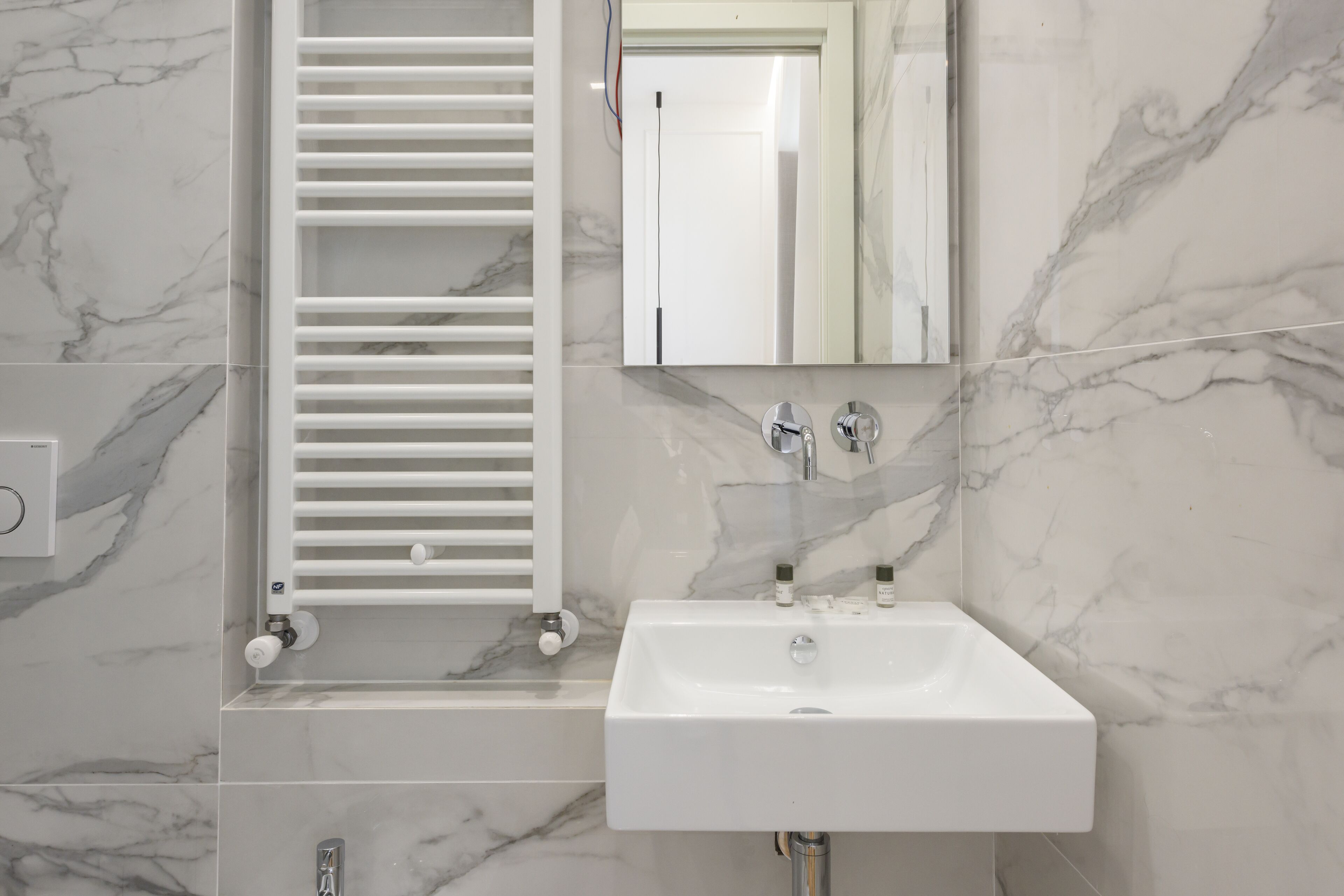 A bathroom with a white sink, a mirror, and a towel rack.