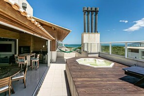 En tagterrasse med træterrasse, jacuzzi og havudsigt.