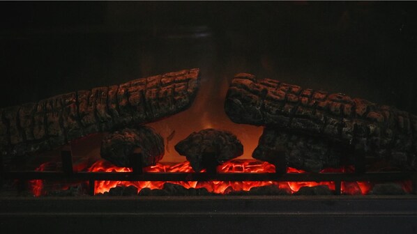 A fireplace with logs and burning embers. - White Oak Creek Cabin (Harrison)