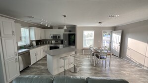 A modern kitchen with white cabinetry, a central island, and a dining area with a table and chairs.