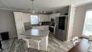 A modern kitchen with white cabinets, stainless steel appliances, and a central island with bar stools.