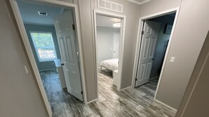 A hallway with wooden flooring, white walls, and doors leading to bedrooms.