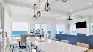 A modern kitchen with a large island, white cabinetry, and a view of the ocean.