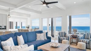 A spacious living room with a large blue sofa, a coffee table, and a view of the ocean.