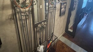 A hallway with a decorative metal gate, a mirror, and a coat rack.
