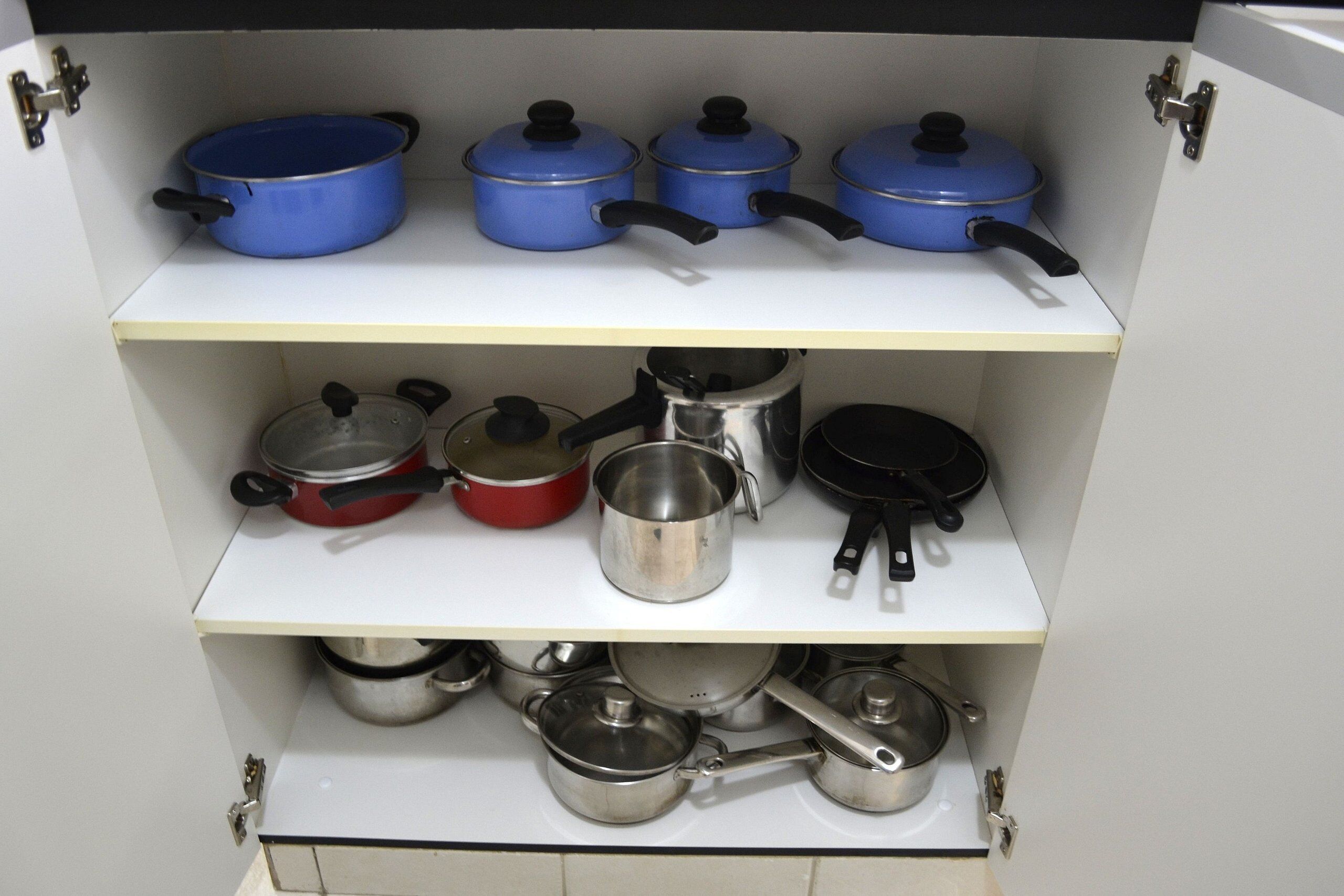 A kitchen cabinet with pots and pans.